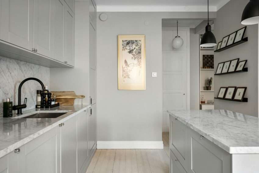 A kitchen with white cabinets and marble counter tops