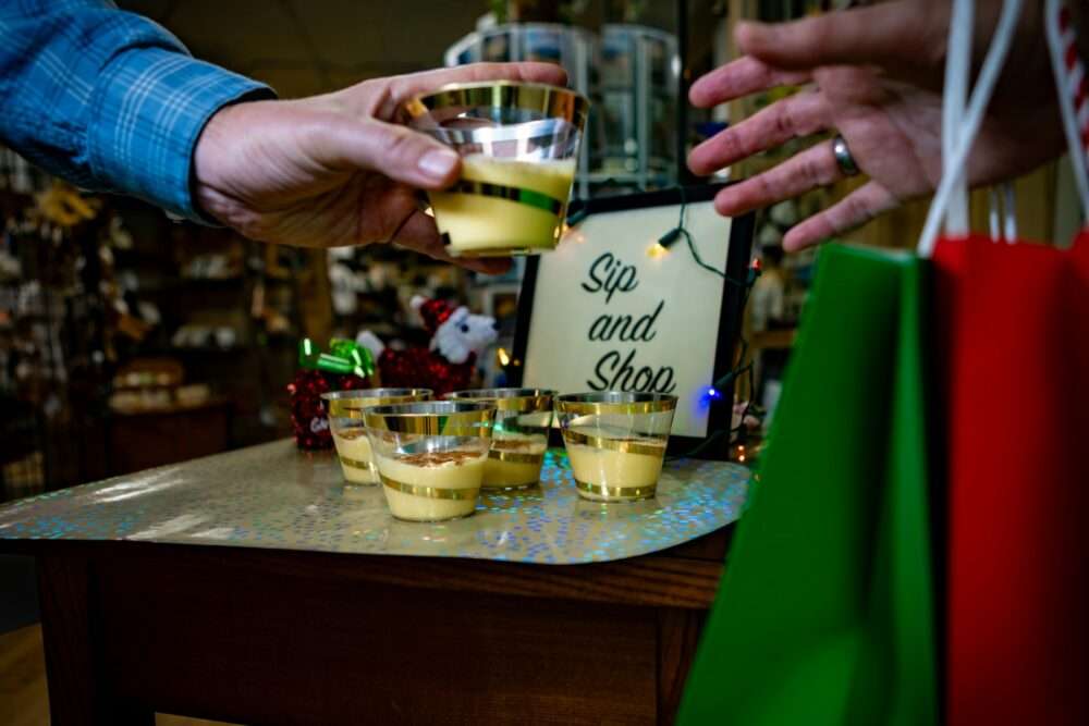 Hands exchange small glasses of yellow liquid