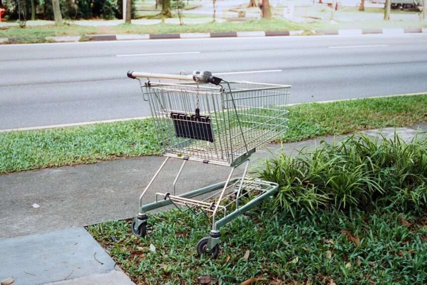 A shopping cart abandoned beside the road.